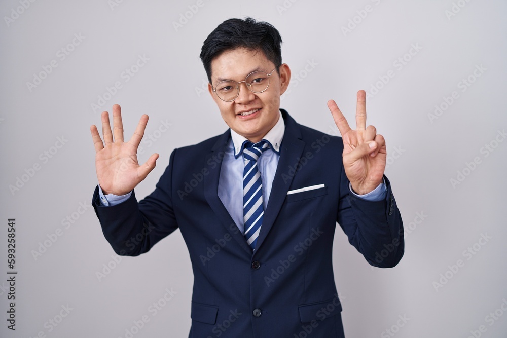 Young asian man wearing business suit and tie showing and pointing up with fingers number seven while smiling confident and happy. Young asian man wearing business suit and tie showing and pointing up with fingers number seven while smiling confident and happy.