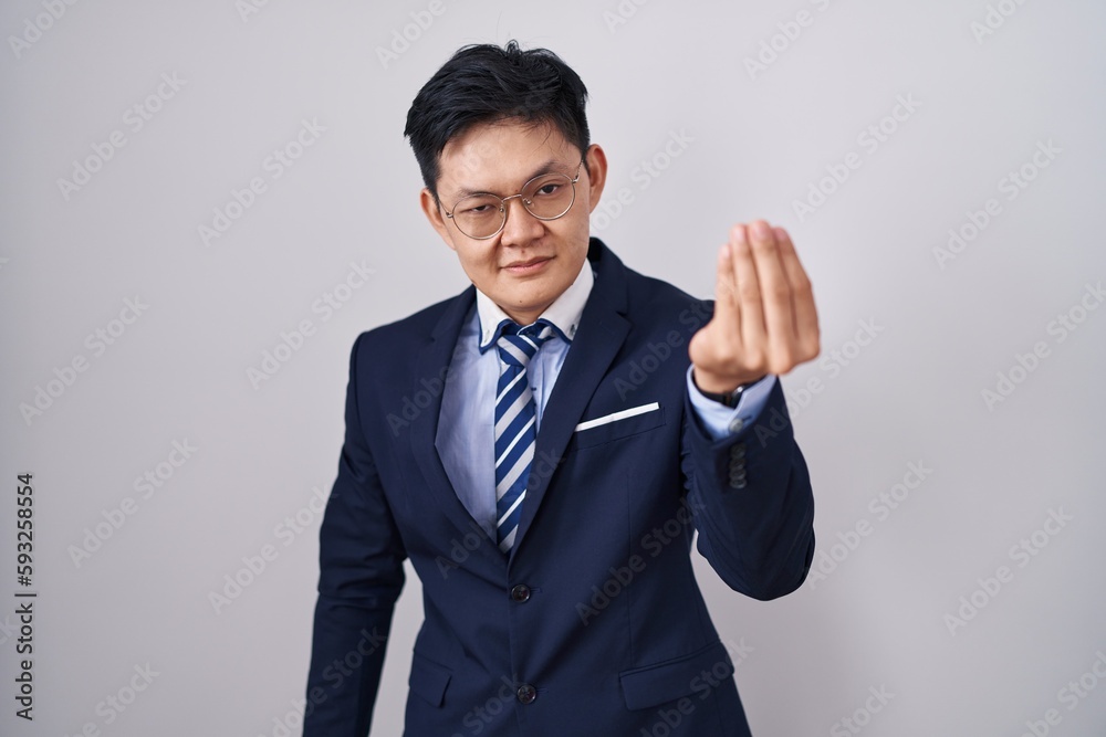 Young asian man wearing business suit and tie doing italian gesture with hand and fingers confident expression Young asian man wearing business suit and tie doing italian gesture with hand and fingers confident expression