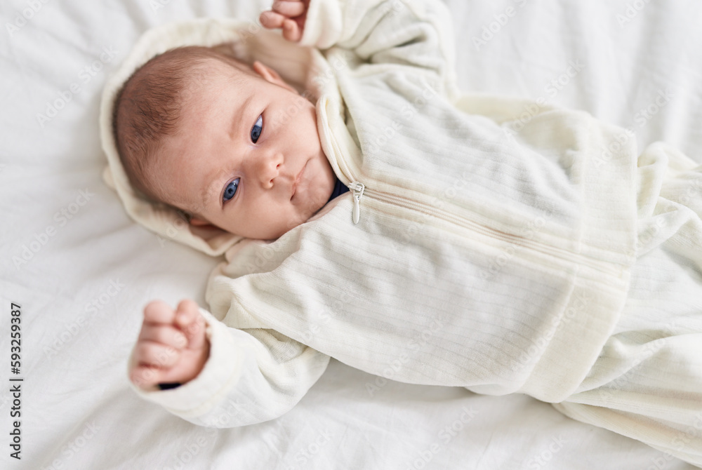 Adorable caucasian baby lying on bed with relaxed expression at bedroom Adorable caucasian baby lying on bed with relaxed expression at bedroom