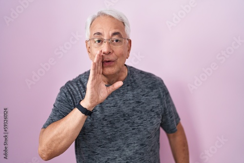 Photos Middle age man with grey hair standing over pink background hand on mouth tellin