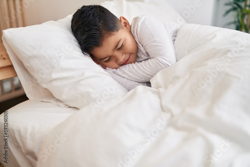 Adorable hispanic boy lying on bed sleeping at bedroom