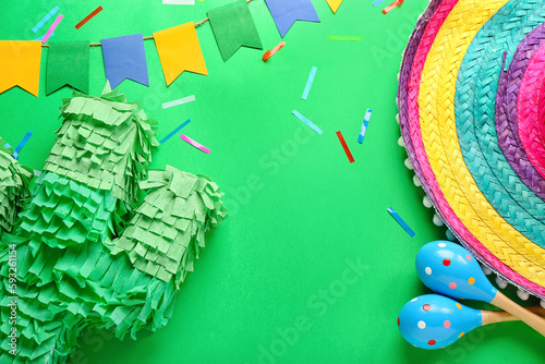 Frame made of Mexican pinata, maracas, sombrero hat and flags on green background