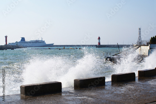 Sea waves breaking on the pier, resort embankment, sun glare on the water, background