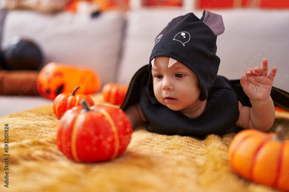 Fototapeta premium Adorable caucasian baby wearing bat costume lying on sofa at home
