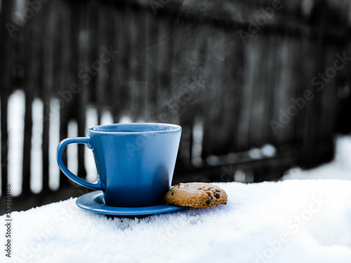 Niebieska filiżanka z ciastkiem na śniegu z gorącą herbatą  