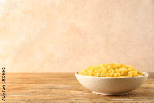 Bowl with raw conchiglie pasta on table photo