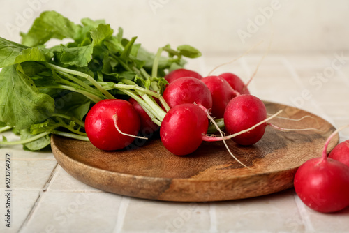 Plate of ripe radish with green leaves on table