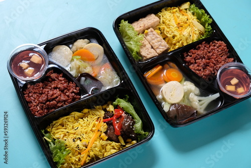 healthy food bento with brown rice, yellow shredded chicken, vegetable soup, tempeh and fruit jelly. For diet weight loss program. healthy lunch menu in a plastic container. catering menu diet. 