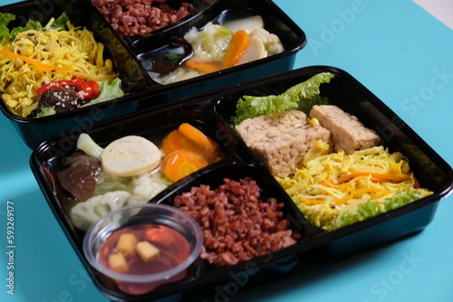 healthy food bento with brown rice, yellow shredded chicken, vegetable soup, tempeh and fruit jelly. For diet weight loss program. healthy lunch menu in a plastic container. catering menu diet. 