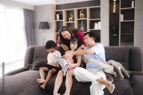 Asian family with father and mother in Father's Day concept, happy daddy and young children having smile and fun together at home, childhood care relationships lifestyle in a house living room