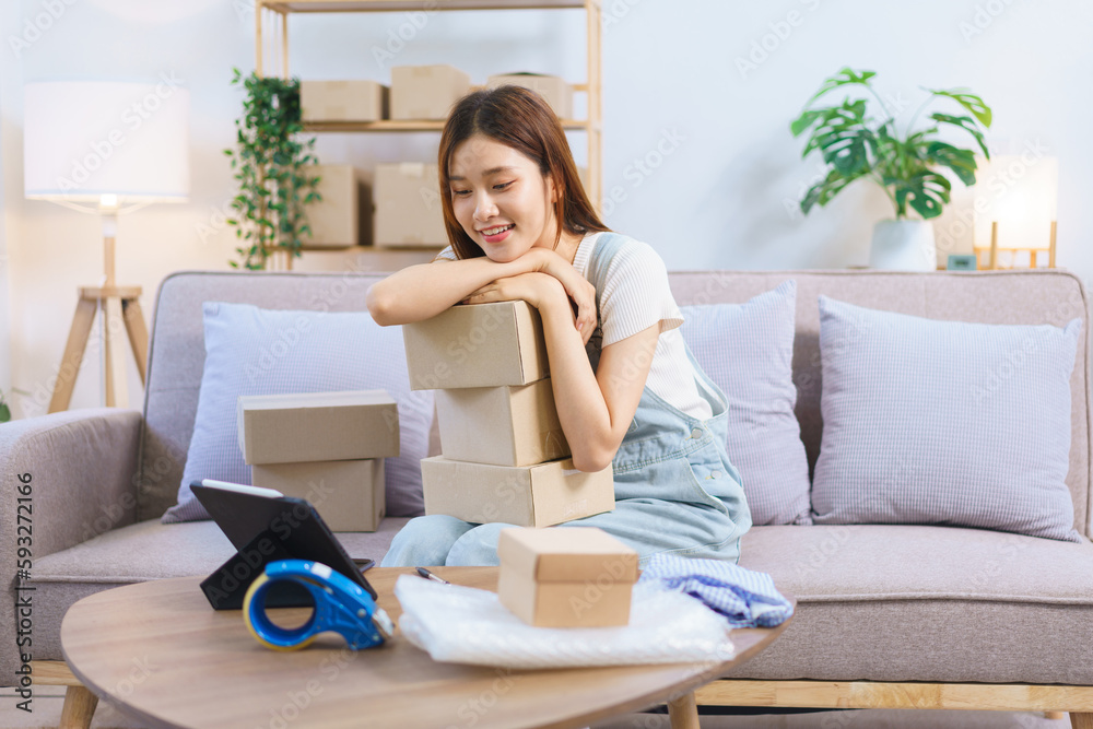 Online merchant concept, Female entrepreneur look data on tablet and prepare parcel boxes to client Online merchant concept, Female entrepreneur look data on tablet and prepare parcel boxes to client
