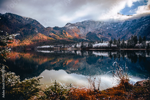 Landscape scene of reflecting Lake Bohinj with trees and mountains at sunset in Slovenia