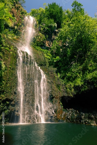 Vertical shot of a waterfall flowing into a pool on the island