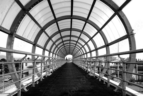 Black and white image of a Pedestrian walkway in the city, metal structure of the ceiling in a walkway