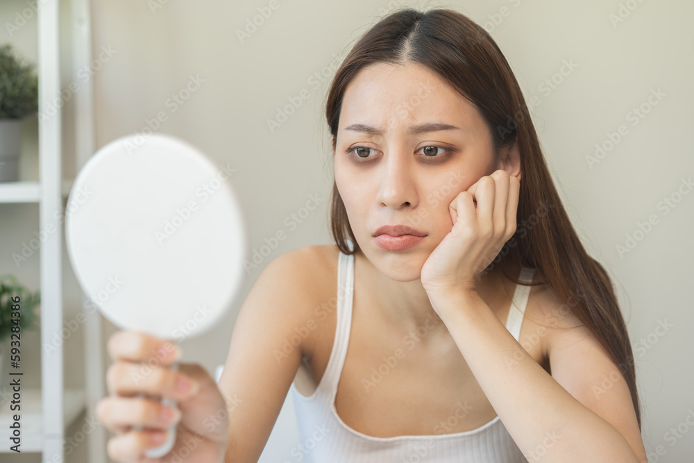 Bored, insomnia asian young woman, girl looking at mirror hand touching under eyes with problem of black circles or panda puffy, swollen and wrinkle on face. Sleepless, sleepy healthcare person. Bored, insomnia asian young woman, girl looking at mirror hand touching under eyes with problem of black circles or panda puffy, swollen and wrinkle on face. Sleepless, sleepy healthcare person.