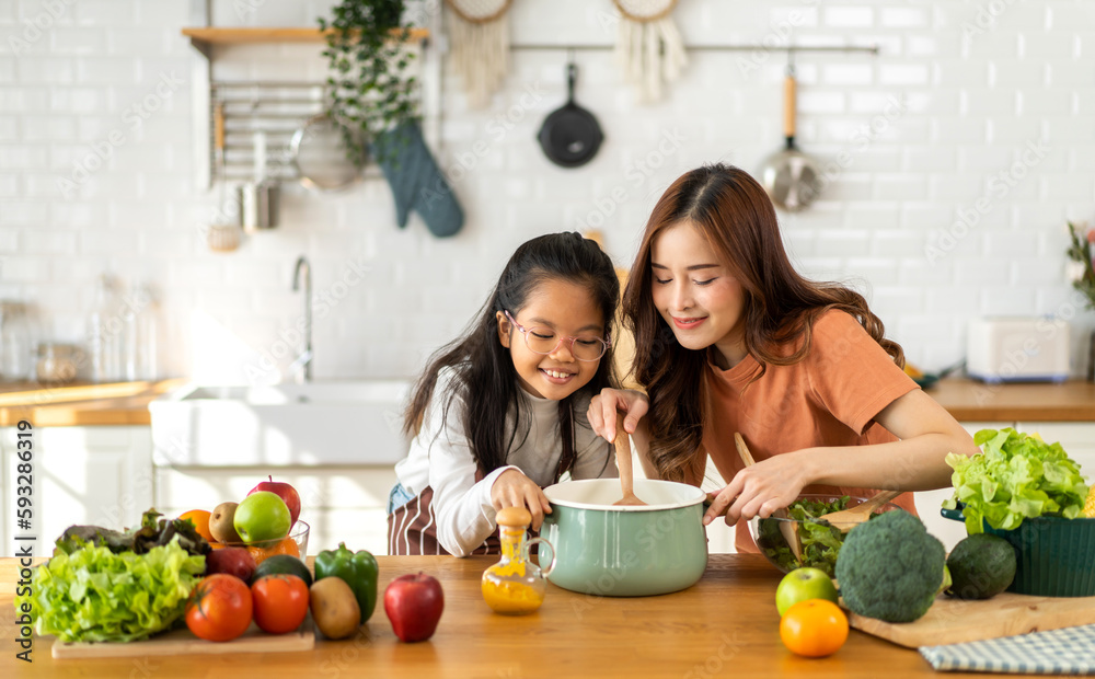 Portrait of enjoy happy love asian family mother with little asian girl daughter child help cook food healthy eat with fresh vegetable testing smell soup in a pot with spoon.helping mommy in kitchen Portrait of enjoy happy love asian family mother with little asian girl daughter child help cook food healthy eat with fresh vegetable testing smell soup in a pot with spoon.helping mommy in kitchen