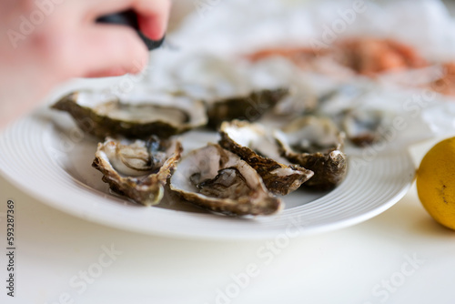 Selective focus of fresh oysters being seasoned on traditional fish market