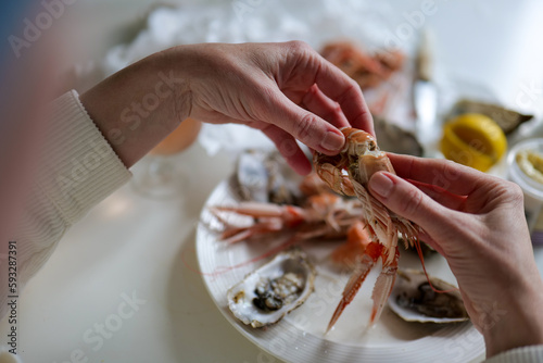 Woman opening prawns above table full of fresh seafood with oysters and prawns and lobster from fish market