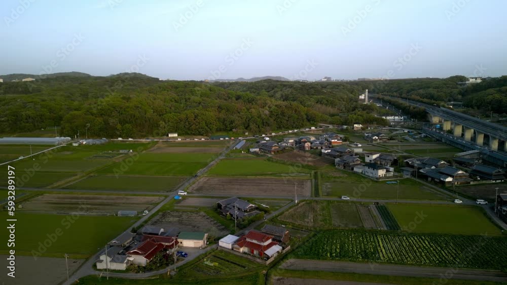 Cars drive on country road in small village by fields and elevated roadway Cars drive on country road in small village by fields and elevated roadway