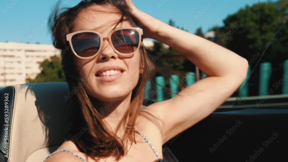 Portrait of young beautiful and smiling hipster female in convertible car. Sexy carefree woman driving cabriolet. Positive model riding and having fun in sunglasses at sunset Portrait of young beautiful and smiling hipster female in convertible car. Sexy carefree woman driving cabriolet. Positive model riding and having fun in sunglasses at sunset