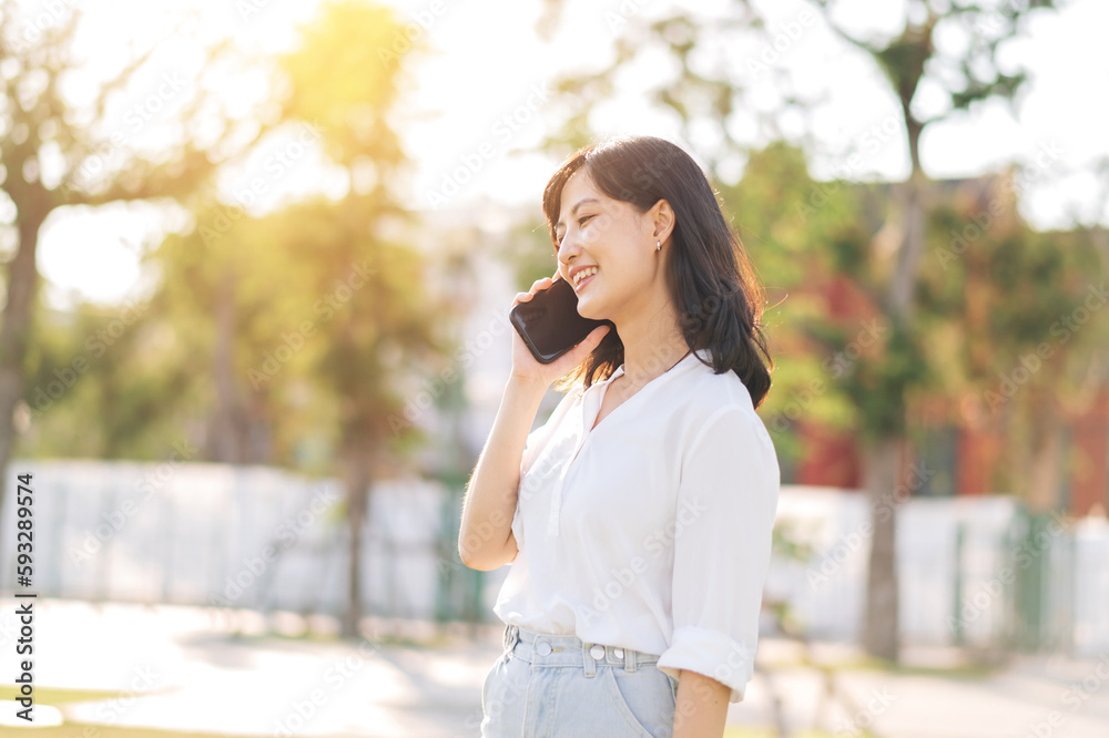 Portrait beautiful young asian woman with smart mobile phone around outdoor nature view in a sunny summer day Portrait beautiful young asian woman with smart mobile phone around outdoor nature view in a sunny summer day