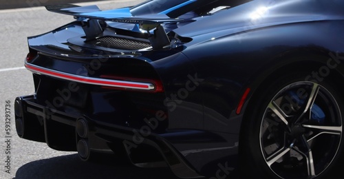 Futuristic sports car tail lights running in daylight/ Elegant supercar rear background image, natural lighting. Exotic hyper car closeup. LED Rear Lights, with copy space.
