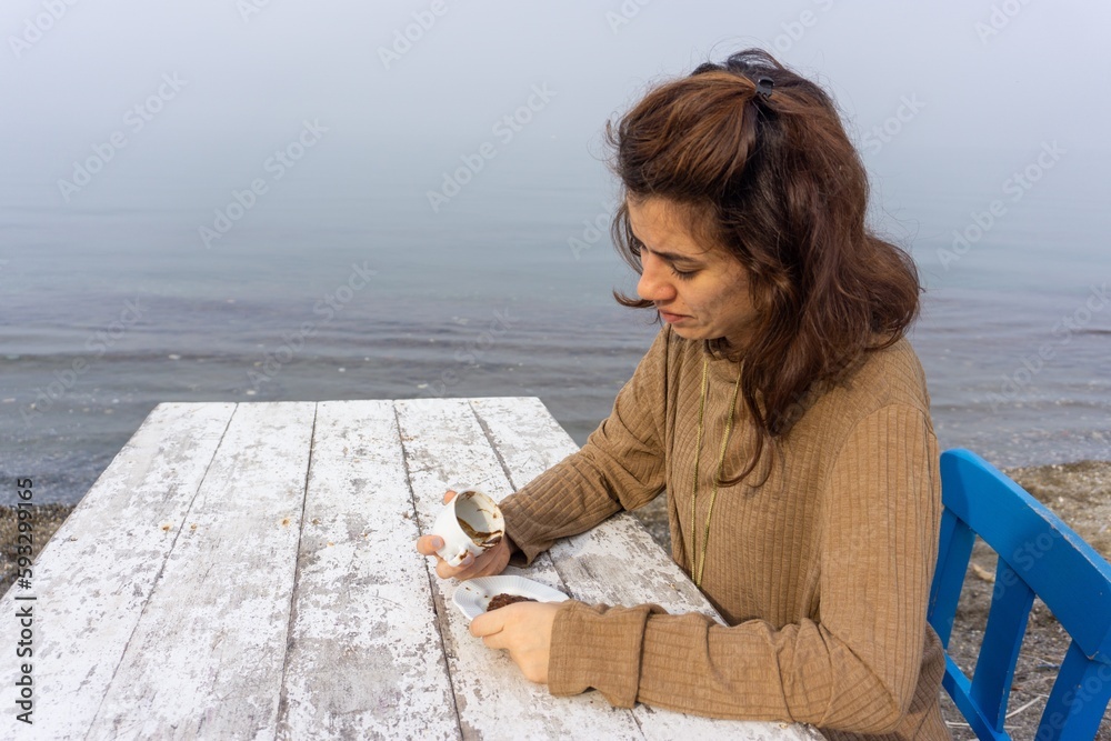 Fortune telling with Turkish coffee concept at beach, woman telling fortune by inspecting the brown grounds remaining in cup. Young girl thinking future forecast on coffee grounds.