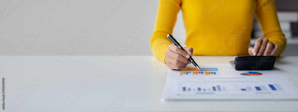 Businessman using a calculator to calculate numbers on a company's financial documents, she is analyzing historical financial data to plan how to grow the company. Financial concept. - obrazy, fototapety, plakaty 