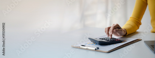 Quadro su tela Businessman using a calculator to calculate numbers on a company's financial documents, she is analyzing historical financial data to plan how to grow the company
