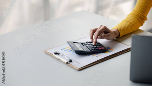 Businesswoman using a calculator to calculate numbers on a company's financial documents, she is analyzing historical financial data to plan how to grow the company. Financial concept. photo