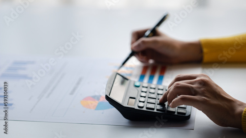 Businessman using a calculator to calculate numbers on a company's financial documents, she is analyzing historical financial data to plan how to grow the company. Financial concept.