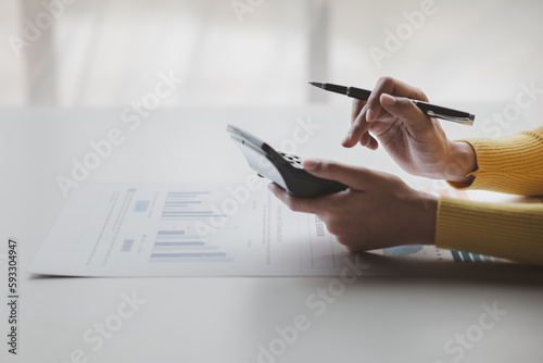 Businessman using a calculator to calculate numbers on a company's financial documents, she is analyzing historical financial data to plan how to grow the company. Financial concept.