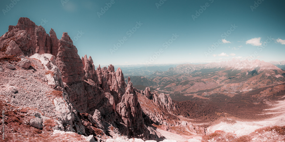 Pink color effect of famous Dolomites mountain peaks. Sharp spiers of Latemar and in the background the Catinaccio and Sciliar massifs, South Tyrol, Italy. Awesome mountain panorama. Fantasy picture