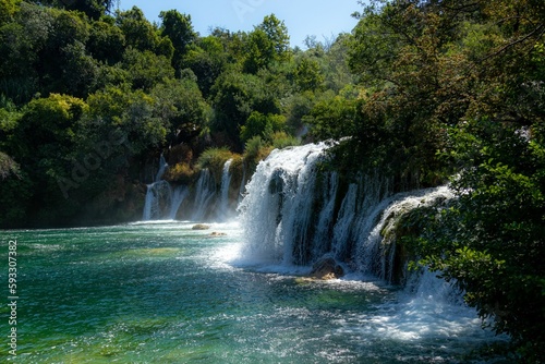 Scenic view of a waterfall flowing through green trees in Krka national park, Croatia on a sunny day