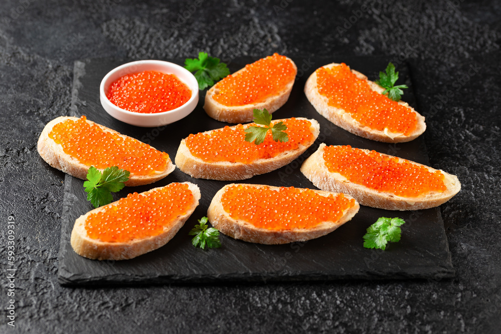 Salmon red caviar sandwiches on rustic stone board Salmon red caviar sandwiches on rustic stone board