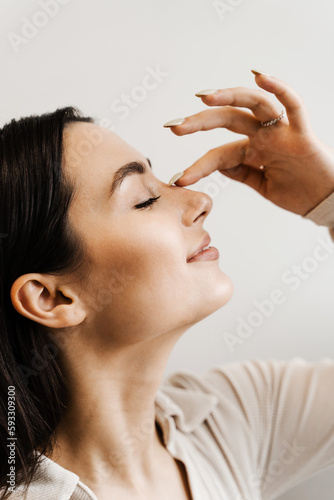 Girl touches her nose and smiles after rhinoplasty nose reshaping surgery for change appearance of the nose and improve breathing.