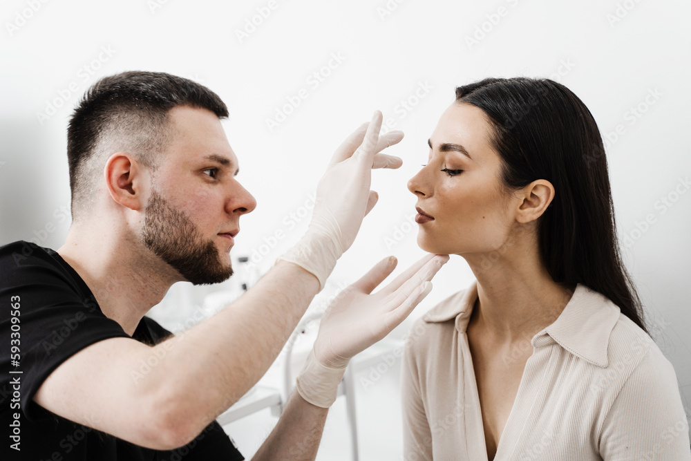 ENT doctor is touching nose and consulting girl patient in medical clinic before septoplasty surgery. Rhinoplasty is reshaping nose surgery for change appearance of the nose and improve breathing. ENT doctor is touching nose and consulting girl patient in medical clinic before septoplasty surgery. Rhinoplasty is reshaping nose surgery for change appearance of the nose and improve breathing.
