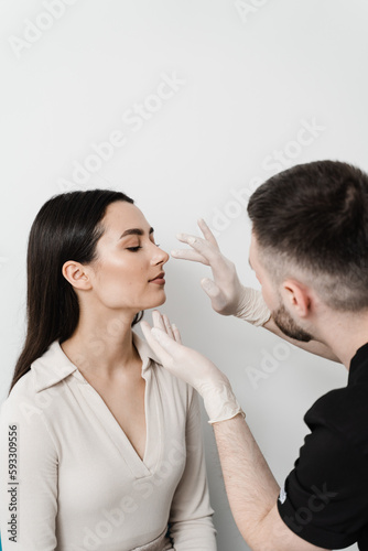 ENT doctor is touching nose and consulting girl patient in medical clinic before septoplasty surgery. Rhinoplasty is reshaping nose surgery for change appearance of the nose and improve breathing.