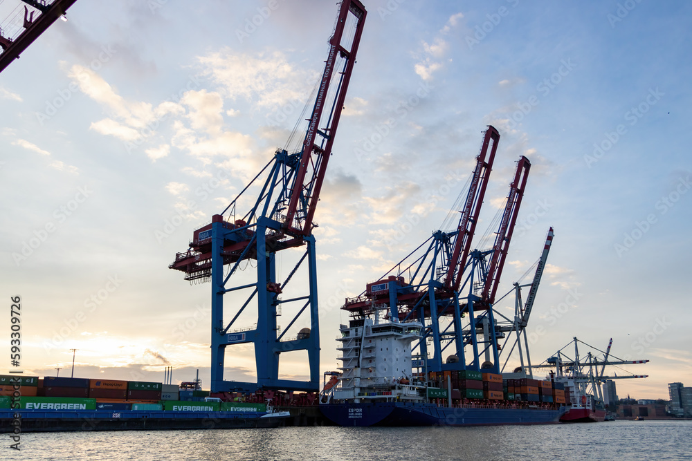 The busy harbour of Hamburg showing a skyline of cranes and container ships at sunset
The busy harbour of Hamburg showing a skyline of cranes and container ships at sunset