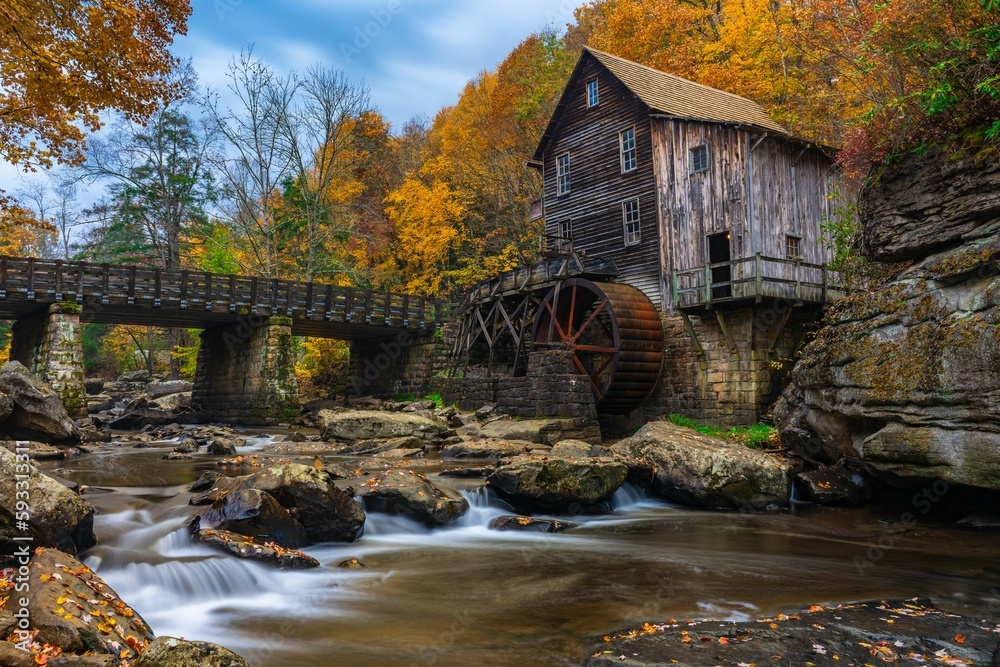 Obraz premium Long exposure of river flowing through Grist Mill at Babcock State Park, West Virginia in autumn