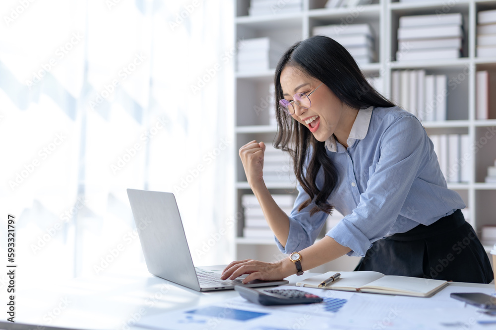 Happy asian businesswoman raising hands with victory smiling happily on laptop computer. The concept of success at work. Happy asian businesswoman raising hands with victory smiling happily on laptop computer. The concept of success at work.