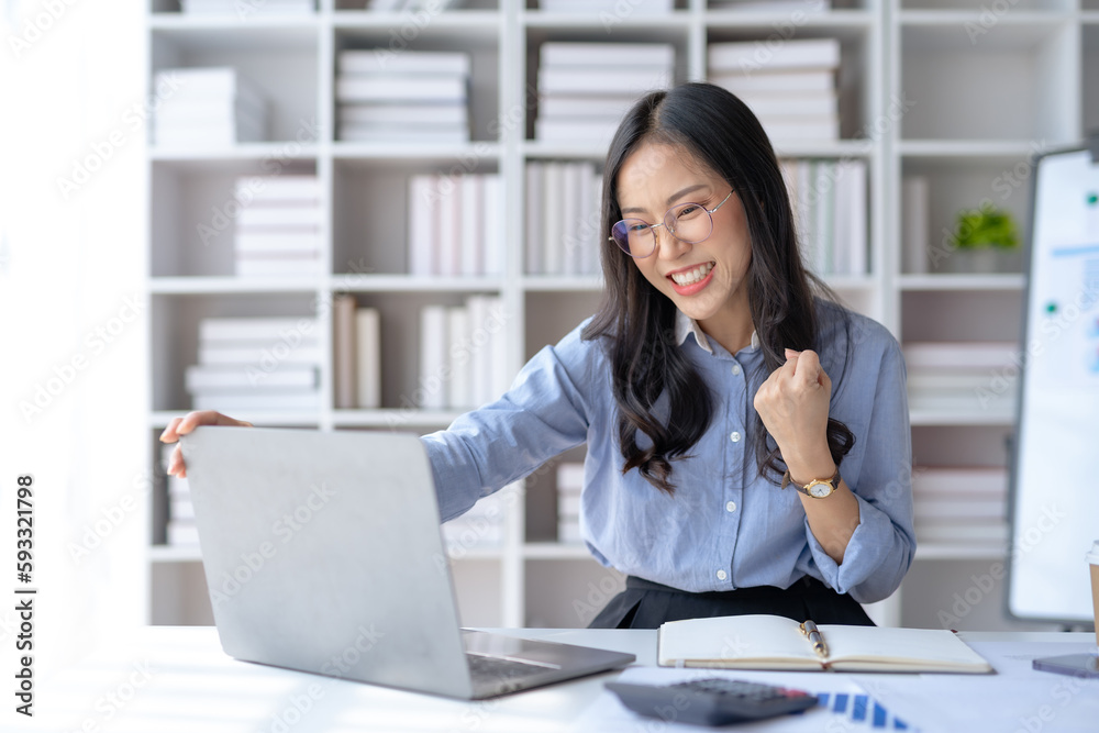 Happy asian businesswoman raising hands with victory smiling happily on laptop computer. The concept of success at work.