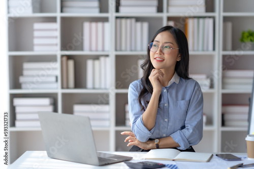 Charming Asian businesswoman working with a laptop at the office. © amnaj