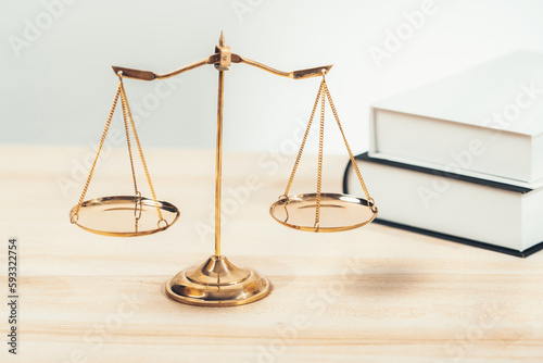 Shiny golden balanced scale and law book on desk in law school as concept justice and legal symbol. Scale balance for righteous and equality judgment by lawyer and attorney. equility photo