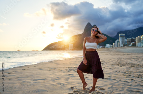 full body portrait young brazilian woman posing and smiling happy on Ipanema beach in Rio de Janeiro at beautiful sunset 