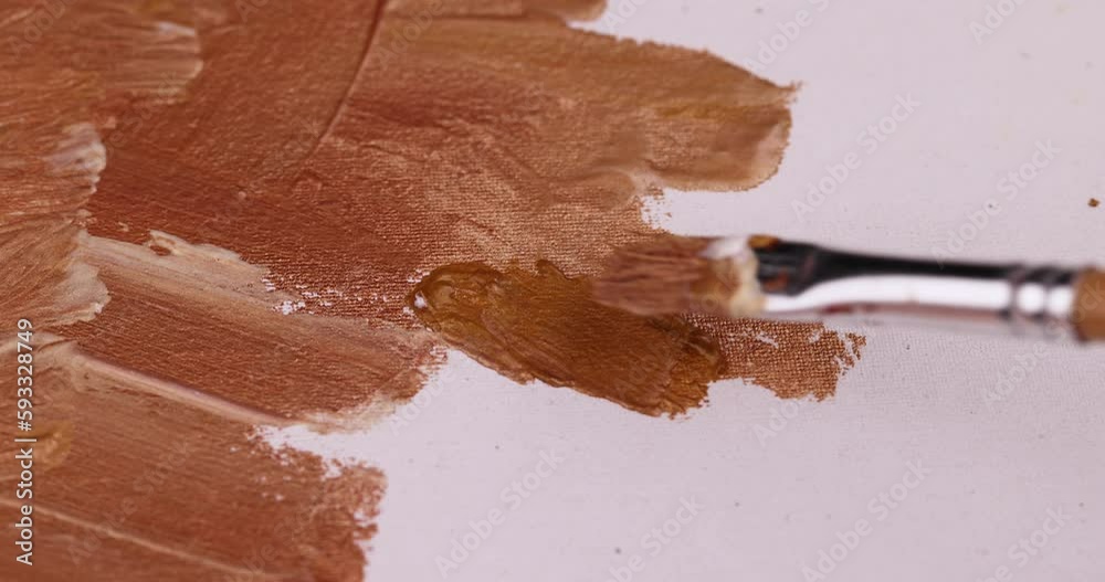 Drawing lines with a brush on a canvas with gold paints, drawing lines