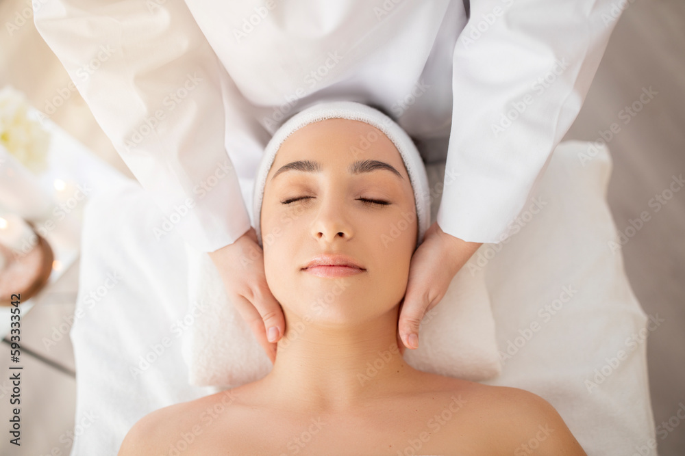 Young indian woman enjoying face lifting massage, top view