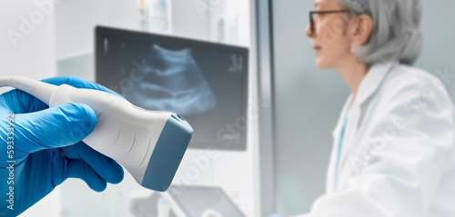 Medical ultrasound probe from ultrasonic machine in doctor's hand on background ultrasound specialist while ultrasound procedure