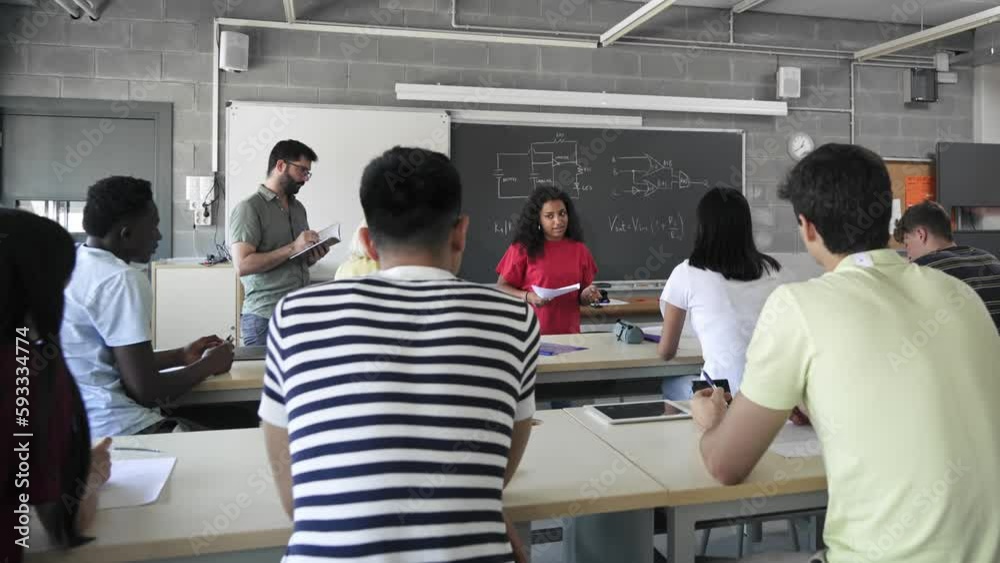 African American college girl student presenting a project reading essay to classmates and teacher at High School classroom