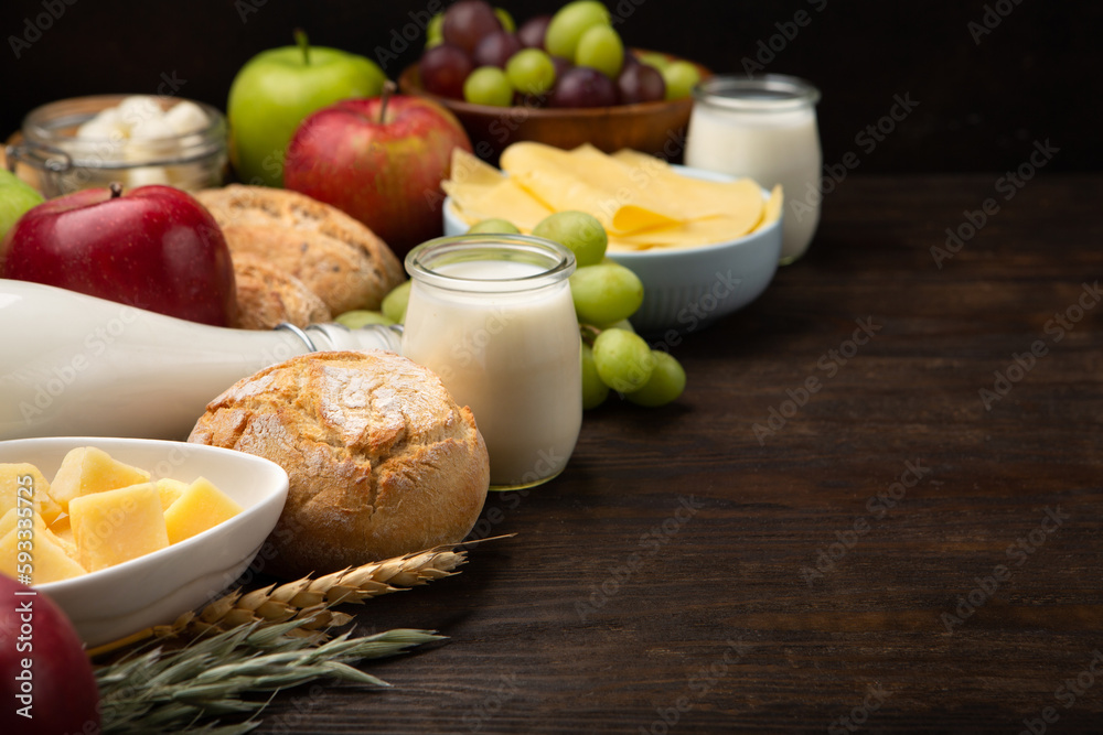 Jewish Shavuot Holiday Card. Dairy Products, Fruits, Cheese, Bread, Milk on Brown Wooden Background. Jewish Shavuot Holiday Card. Dairy Products, Fruits, Cheese, Bread, Milk on Brown Wooden Background.